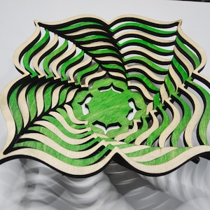 Puede incluir: Un cuenco decorativo de madera con un diseño en capas. El cuenco presenta capas alternas de verde, negro y tonos de madera natural. El cuenco tiene una forma única y orgánica, y es adecuado para la decoración del hogar.