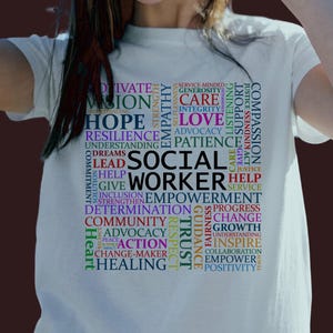 May include: A white t-shirt with a colorful word cloud design that reads "Social Worker". The word cloud includes words like "compassion", "hope", "empowerment", "justice", "trust", "action", and "healing".
