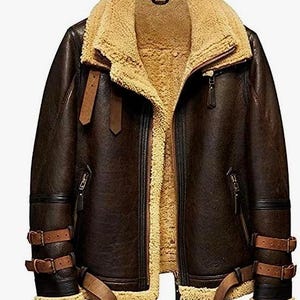 May include: A brown leather jacket with a tan shearling lining and collar. The jacket features a zip-up front, multiple pockets, and adjustable straps on the sleeves and waist. The jacket has a classic aviator style.