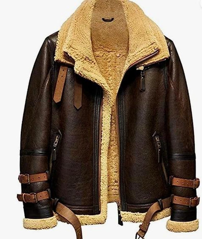 May include: A brown leather jacket with a tan shearling lining and collar. The jacket features a zip-up front, multiple pockets, and adjustable straps on the sleeves and waist. The jacket has a classic aviator style.