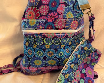 May include: A blue and pink floral print drawstring backpack with a zippered pocket and a matching smaller pouch. The backpack has a blue and white strap and a metal buckle.
