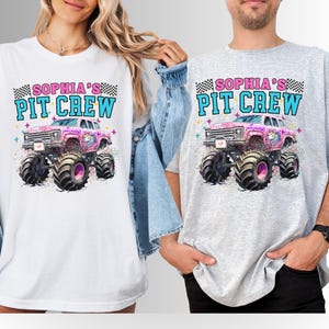May include: White and gray t-shirts featuring a colorful graphic of a pink monster truck with a unicorn design. The text "SOPHIA'S PIT CREW" is printed above the truck in blue and pink, with a checkered flag design. The shirts are worn by two people.
