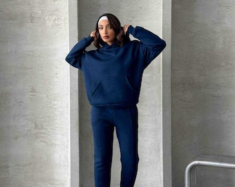 May include: A navy blue hooded sweatshirt and matching sweatpants. The sweatshirt has a kangaroo pocket and the sweatpants have a straight leg.