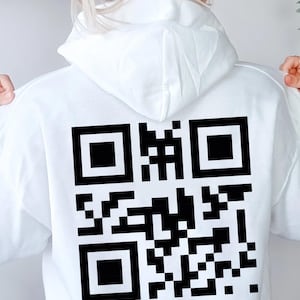 Könnte beinhalten: Weißer Kapuzenpullover mit einem großen schwarzen QR-Code auf dem Rücken. Der QR-Code ist ein quadratisches Muster aus schwarzen und weißen Quadraten. Der Hoodie hat eine Kapuze und lange Ärmel.
