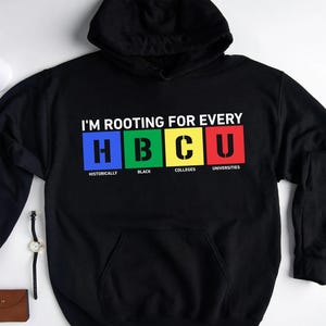 May include: Black hoodie featuring the text "I'M ROOTING FOR EVERY HBCU" in white. The letters HBCU are in blue, green, yellow, and red boxes. The words "Historically", "Black", "Colleges", and "Universities" are below the letters.