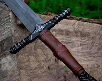 May include: A black and brown sword with a decorative handle and a silver inscription that reads "The Lord of the Rings - The Hobbit".