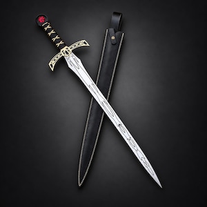 Peut inclure: Une épée en acier argenté dotée d'une poignée gainée de cuir noir, d'une garde dorée et d'un pommeau orné d'une pierre rouge circulaire. La lame présente des motifs gravés et est accompagnée d'un fourreau en cuir noir assorti.