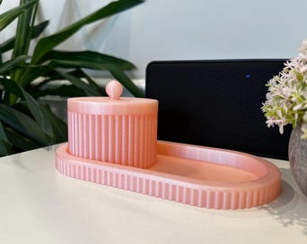 Puede incluir: Una bandeja ovalada de color rosa con un recipiente con tapa a juego de color rosa. La bandeja y el recipiente tienen una textura acanalada.
