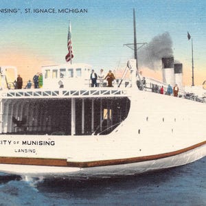 May include: Vintage postcard featuring the white ferry boat "City of Munising" sailing on blue water. The boat has passengers on deck, an American flag, and the text "City of Munising, Lansing" and "St. Ignace, Michigan".