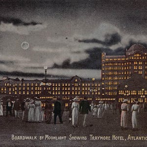 May include: Vintage postcard depicting the Traymore Hotel in Atlantic City, New Jersey, at night. The image shows a large building illuminated by many lights, with people strolling on the boardwalk under a moonlit sky. The text "BOARDWALK BY MOONLIGHT SHOWING TRAYMORE HOTEL, ATLANTIC CITY, N.J." is visible.