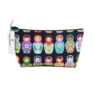 May include: Black zippered pouch with a colorful pattern of nesting dolls. The pouch has a white tag with the text "Fireball Creations".