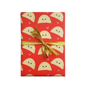 May include: Red gift wrap with a gold ribbon and a pattern of smiling dumplings with pink hearts.