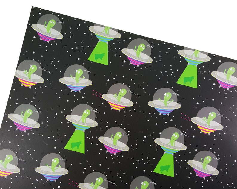 May include: Black and white wrapping paper with a repeating pattern of green aliens in flying saucers. The aliens are saying "MIIKEE" and "NEW-PEW-NEW". There are also green cows on the paper.