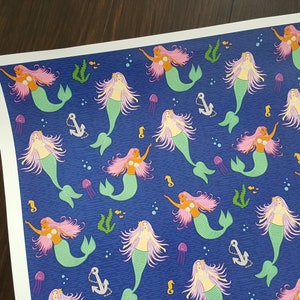 May include: A blue background with a repeating pattern of mermaids with pink hair and green tails. The mermaids are swimming in a sea of blue with white bubbles and seahorses.