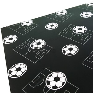 Puede incluir: Papel de regalo negro y blanco con un patr&oacute;n repetido de balones de f&uacute;tbol y campos de f&uacute;tbol.