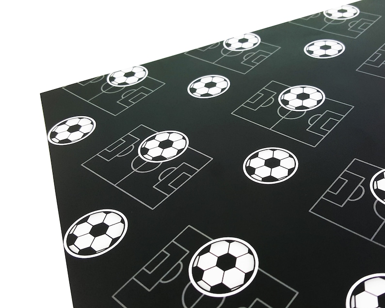 Puede incluir: Papel de regalo negro y blanco con un patr&oacute;n repetido de balones de f&uacute;tbol y campos de f&uacute;tbol.