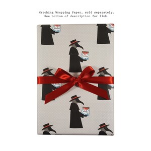 May include: A grey gift wrap with a repeating pattern of black plague doctors holding jars labelled "Kittler". The gift wrap is tied with a red ribbon.