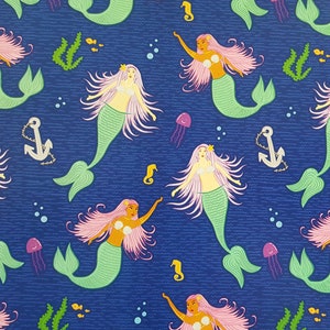 May include: A seamless pattern featuring mermaids with pink hair and green tails on a dark blue background. The mermaids are surrounded by seahorses, seashells, and seaweed.
