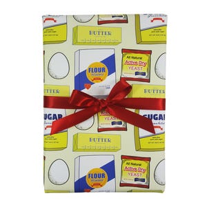 May include: A yellow and white wrapping paper with a repeating pattern of kitchen staples, including butter, flour, sugar, and yeast. The paper is tied with a red ribbon.