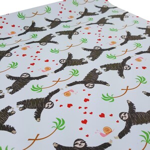 May include: White wrapping paper with a repeating pattern of sloths hanging from palm trees with red hearts and snails.