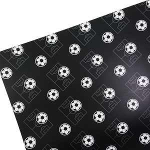 Puede incluir: Papel de regalo negro con un patr&oacute;n blanco repetido de balones de f&uacute;tbol y campos de f&uacute;tbol.