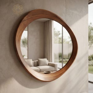 May include: A wall-mounted mirror featuring an organic, asymmetrical, rounded wooden frame with a smooth, polished brown grain finish. The reflective glass surface captures a view of a living room interior with a sofa and window light.