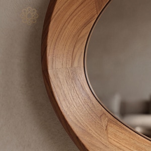 May include: A circular wall mirror featuring a wide, polished wooden frame with a prominent natural grain pattern. The frame is constructed from several segments of light to medium brown wood joined together, surrounding a reflective glass surface.
