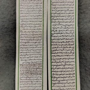 May include: Two rectangular bookmarks with ornate floral and geometric designs. The bookmarks feature Arabic script and are likely religious or cultural items. The top of each bookmark has a decorative arch.