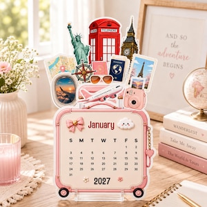 Può includere: Un calendario di gennaio 2027 a forma di valigia rosa, decorato con ritagli a tema viaggio tra cui la Statua della Libertà, una cabina telefonica rossa, il Big Ben, una bussola, un passaporto, occhiali da sole, un aereo e una fotocamera rosa.