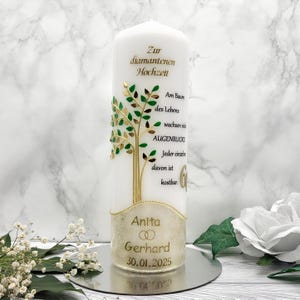 Könnte beinhalten: Eine weiße Kerze mit einem goldenen und grünen Baumdesign. Die Kerze trägt den Text "Zur diamantenen Hochzeit" und "Am Baum des Lebens wachsen viele Augenblicke. Jeder einzelne davon ist kostbar." Der Boden der Kerze trägt den Text "Anita Gerhard 30.01.2025".