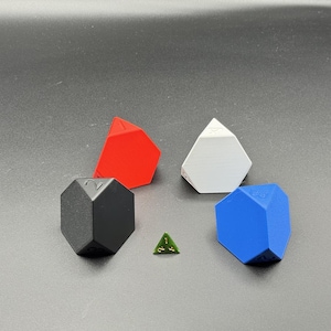 May include: A collection of polyhedral dice in various colors: red, white, black, and blue. Each die has a unique geometric shape. A small green triangular die is also present.