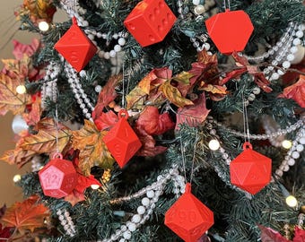 Puede incluir: Un árbol de Navidad decorado con adornos rojos en forma de dados. Los adornos son varios dados poliédricos, incluyendo un dado de seis caras, un dado de diez caras y un dado de doce caras. El árbol está adornado con guirnaldas de cuentas blancas y hojas de colores otoñales.