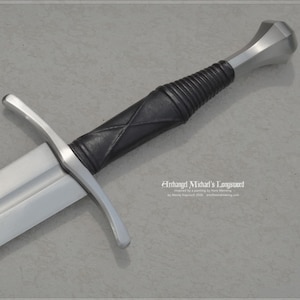 Può includere: Una spada lunga con una lama argentata e un'impugnatura avvolta in pelle nera. L'elsa e il pomo sono argentati. Il testo "Archangel Michael's Longsword" è visibile sul lato destro dell'immagine.
