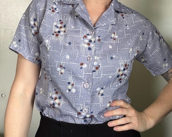 Blusa vintage de los años 60 en color azul bígaro con estampado floral en forma de estrella y botones, con bolsillos.