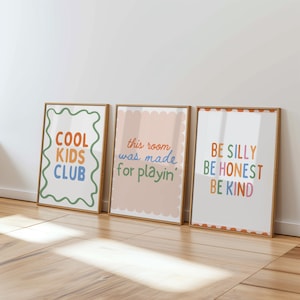 May include: Three framed art prints with inspirational quotes. The first reads "COOL KIDS CLUB" in orange, blue, and green. The second says "this room was made for playin'" in pink and green. The third says "BE SILLY BE HONEST BE KIND".