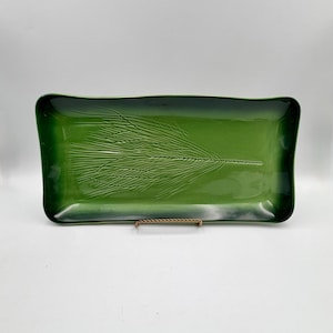 May include: A rectangular, glossy green ceramic tray with a raised, textured fern leaf design. The tray has rounded corners and a dark green border. The design is centered on the tray.