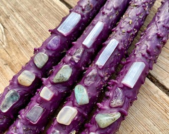 Puede incluir: Cuatro velas moradas con cristales y varitas de selenita incrustados. Las velas están decoradas con varios cristales, incluyendo amatista, labradorita y cuarzo claro.