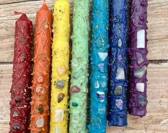 May include: Seven colorful candles with embedded crystals, arranged in a rainbow pattern from red to purple. Each candle is approximately 6 inches long and has a unique crystal design.
