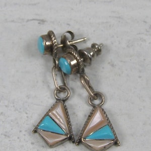 May include: Silver-toned earrings with turquoise and mother-of-pearl inlays. Each earring features a small turquoise stone at the top, connected by a chain to a triangular pendant with a turquoise and mother-of-pearl design. The earrings have a post-back closure.