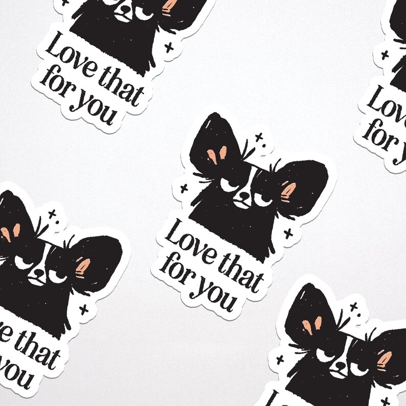 May include: A collection of white stickers featuring a black and white illustration of a dog with large ears and the text "Love that for you." The dog has a grumpy expression. Small plus signs are scattered around the dog.