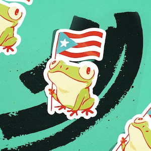May include: A sticker featuring a cartoon frog holding a Puerto Rican flag. The frog is green and cream-colored with large eyes. The flag has red and white stripes with a blue triangle and white star. The background is teal with black brushstrokes.