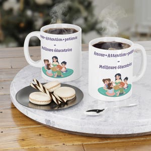 Peut inclure: Deux tasses en céramique blanche avec une illustration colorée d'une enseignante et d'enfants. Le texte sur les tasses est "Amour + Attention + Patience = Meilleure éducatrice".