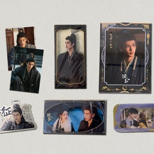 May include: Collection of various fan-made merchandise featuring images of a man in traditional Asian attire. Items include photo cards, a metal charm, and a small rectangular print with a couple.