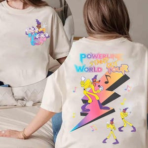 May include: White t-shirt with a cartoon character graphic on the front and "POWERLINE STAND OUT WORLD TOUR" text on the back.