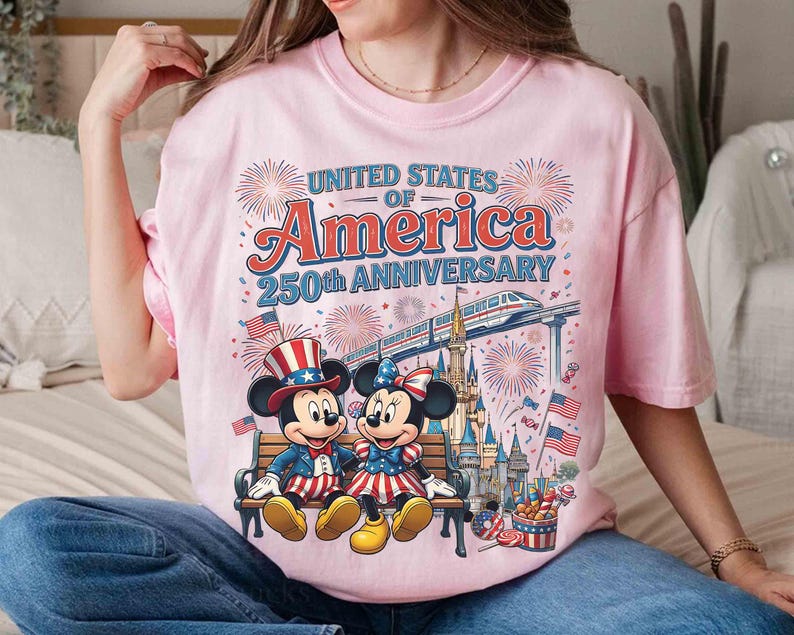 Może przedstawiać: Jasnor&oacute;żowa koszulka z Myszką Miki i Minnie w patriotycznych strojach, siedzących na ławce. Koszulka zawiera napis "United States of America 250th Anniversary" z fajerwerkami i pociągiem.
