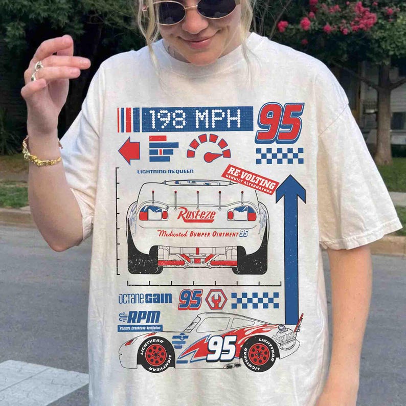K&ouml;nnte beinhalten: Ein cremefarbenes Kurzarm-T-Shirt mit einem Grafikdruck eines Rennwagens. Das Design enth&auml;lt den Text 198 MPH, 95, Rust-eze, Medicated Bumper Ointment, Octane Gain, RPM und Re-Volting sowie verschiedene Symbole und Icons aus dem Rennsport.
