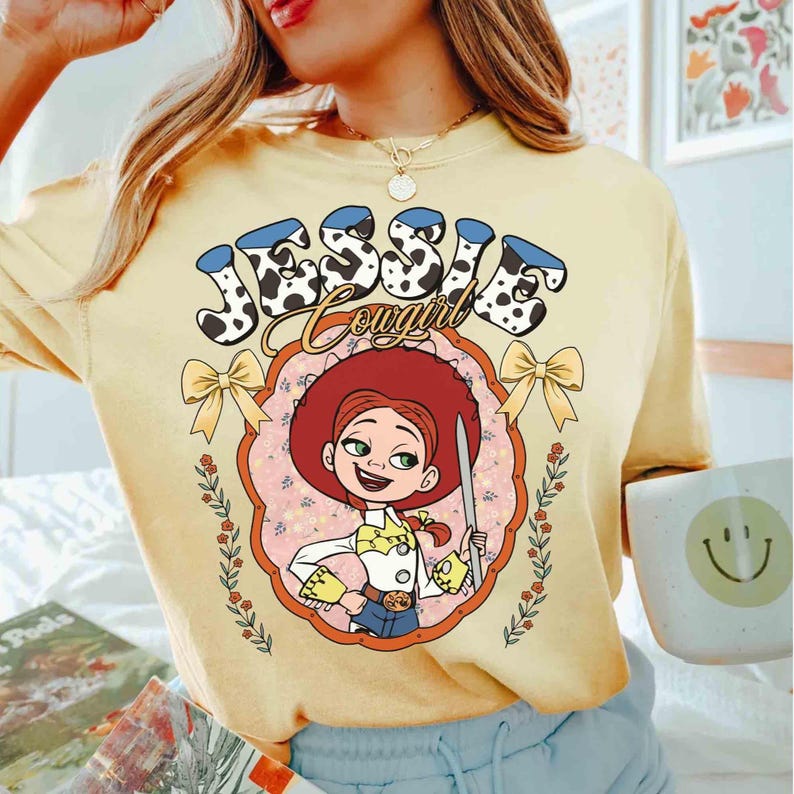 May include: A yellow t-shirt with a cartoon image of Jessie from Toy Story. The text "Jessie Cowgirl" is printed on the shirt in a black and white cow print.