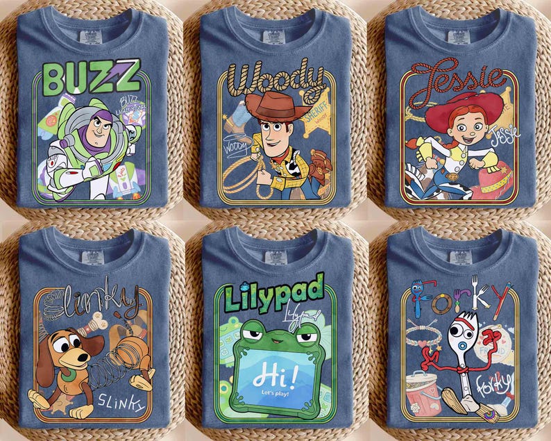 May include: Six blue t-shirts featuring Toy Story character graphics. The shirts display Buzz Lightyear, Woody, Jessie, Slinky Dog, a green frog named Lilypad, and Forky. Each design includes the character name in stylized text within a rectangular frame.