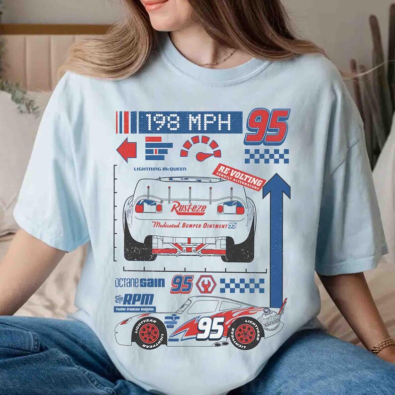 K&ouml;nnte beinhalten: Ein hellblaues T-Shirt mit einem Grafikdruck eines Rennwagens mit der Nummer 95, dem Text Rust-eze, Medicated Bumper Ointment, 198 MPH, Revolting, Octane Gain und RPM. Das Design enth&auml;lt einen Tachometer, Pfeile und karierte Muster.