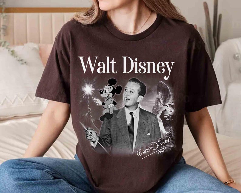Puede incluir: Una camiseta de manga corta de color marr&oacute;n oscuro con un gr&aacute;fico de estilo vintage de Walt Disney en traje y corbata, con Mickey Mouse sobre su hombro. El texto Walt Disney aparece en blanco sobre el gr&aacute;fico, con una firma en la parte inferior.